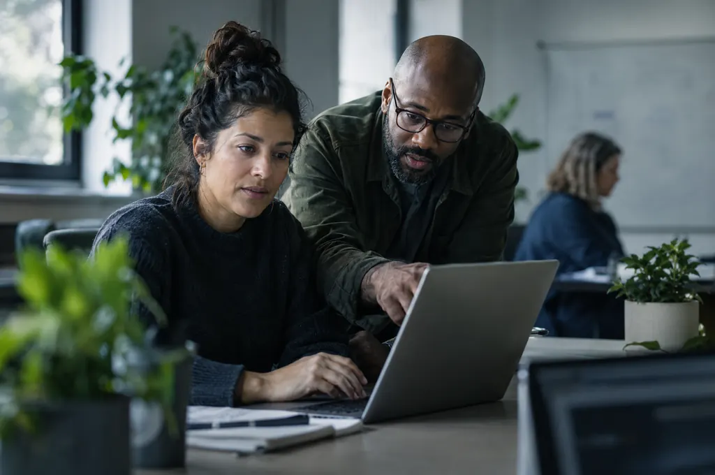Two association staff members working through something on a laptop